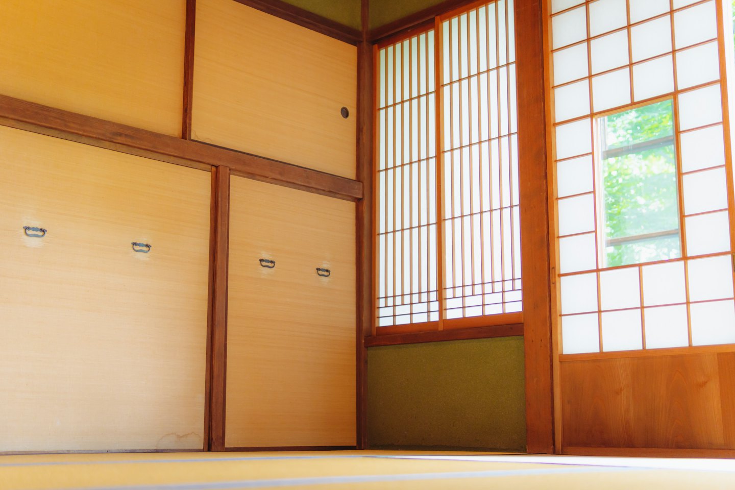 Stanza tatami con porte scorrevoli e fogliame verde all'esterno.